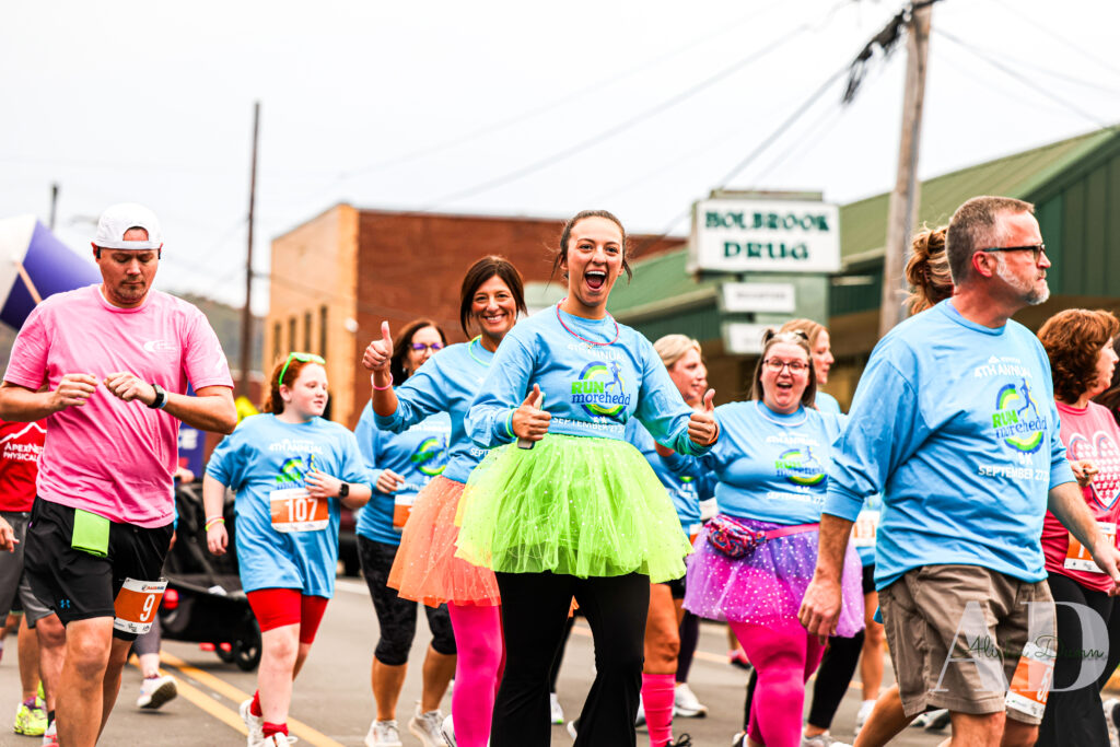 Participants in colorful attire walk and run in a community charity event on a street.